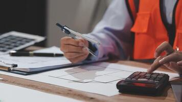 A person in an orange vest is using a calculator and pen video
