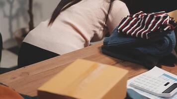 A woman is sitting at a desk with a pile of clothes video