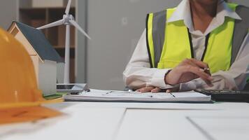 A woman in a hard hat and safety vest is working on a calculator video