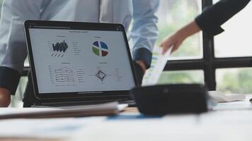 Two people standing in front of a laptop with graphs on it video