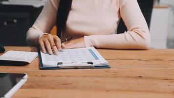 A woman is sitting at a desk with a notebook and a calculator video