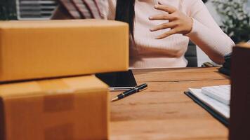 A woman is working at her desk with boxes and a laptop video
