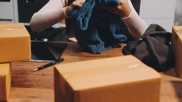A woman is sitting at a table with boxes and a laptop video