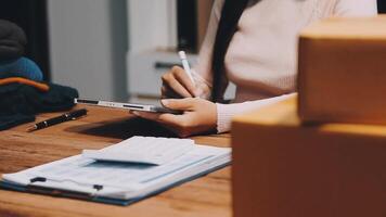A woman is writing on a notebook while sitting at a desk with boxes and other items video