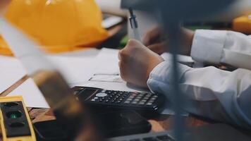 A person is working on a project with a calculator and a hard hat video