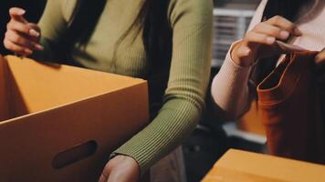 Two women are holding boxes and one is putting something in it video