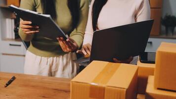 Two women are working on a laptop and a box video