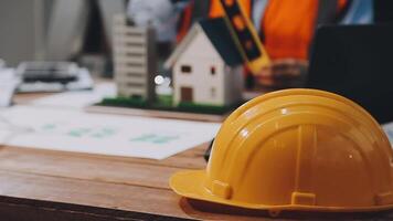 A hard hat sitting on a table with a laptop and a construction worker video