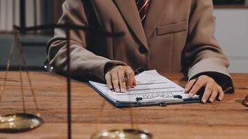 A woman in a suit is sitting at a desk with a paper and a scale video