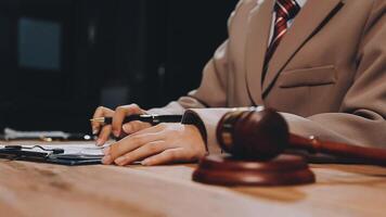 A judge's gavel is sitting on a desk next to a pen and paper video