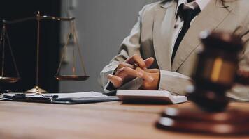 A woman in a suit is sitting at a desk with a scale and a gavel video