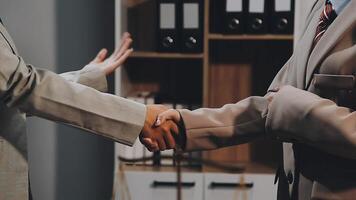 Two business people shaking hands in an office video