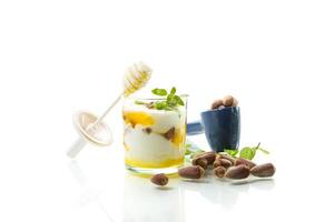 Diet breakfast. homemade yogurt with kiwi, honey and nuts in a glass, isolated on white background photo