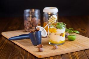 homemade yogurt with kiwi, honey and nuts in a glass on a wooden table . Side view. photo