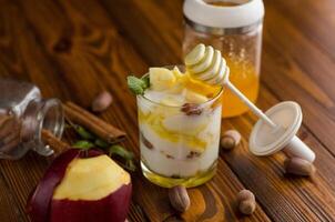 sweet homemade yogurt in a glass with apples, nuts and honey. Side view. photo