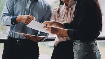 Three business people standing around a table with papers video