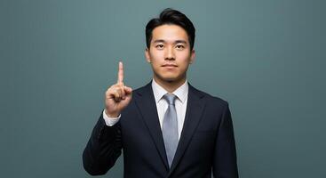 Asian businessman pointing upwards in navy suit - Generated using AI photo
