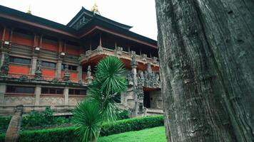 A beautiful view of a traditional Balinese temple with intricate carvings, surrounded by lush greenery and palm-like plants. The architecture features ornate details and a serene atmosphere video