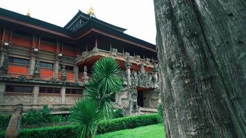 A traditional Balinese temple with intricate carvings and lush greenery surrounding it. The temple features ornate architecture and is set against a cloudy sky video
