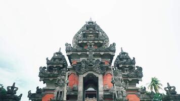 A majestic Balinese temple with intricate stone carvings and statues, showcasing traditional architecture against a cloudy sky video