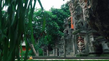 A serene view of a traditional Balinese temple courtyard, featuring intricate stone carvings, lush greenery, and a tranquil atmosphere video