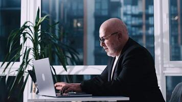 Angry man in glasses swearing and cursing against information technology. Concept of hating computers. Businessman in a suit in the office punches the keyboard. Bad deal video