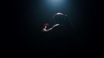 Woman boxer in dark room practicing shadow boxing, female fighter practicing fast punches with back light in slow motion video