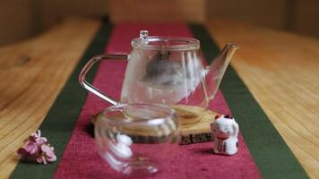 A glass teapot and cup rest on a wooden table, creating a cozy vibe. Media video