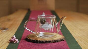 An Elegant Glass Teapot on a Wooden Table Setting, creating an inviting ambiance. Media video