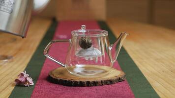 A calming shows a teapot brewing on a wooden table. Media video