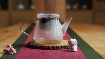 An Elegant Teapot Beautifully Displayed with Blossoms on a Rustic Wooden Table Surface. Media video