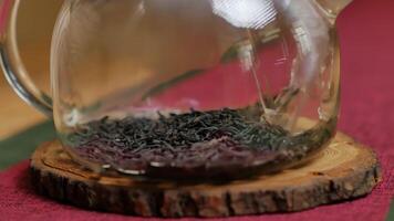 A glass teapot on a wooden table captures the calming tea process. Media video