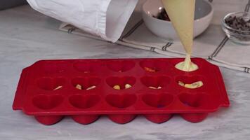 Preparing homemade chocolate in red silicone molds on countertop video