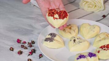 Manual presented chocolate sweets with drier strawberries and nuts, with flowers on a plate video