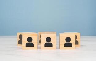 Wooden cubes with people icons over a marble table with a light blue background photo