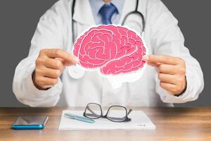 Doctor in a uniform holding a brain symbol while sitting at the table photo