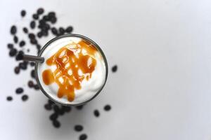 Ice caramel latte with coffee beans isolated on white background top view closeup photo