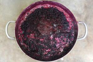 Boiling mulberry jam in metal saucepan on the open fire photo