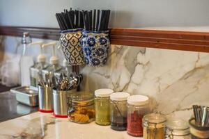 Details of interior in a coffee shop, many plastic straws for a drink, spoons and jars with matcha, jam, red velvet photo