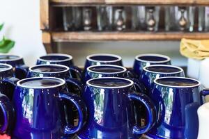 Many blue cups in a row on the woden shelf in the kitchen photo