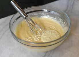 Egg beater in a glass bowl mixing dough photo
