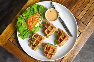 Belgian waffles on a white plate with greens on wooden background photo