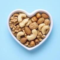 heart shaped bowl filled with variety of mixed nuts, including cashews, almonds, and walnuts, creates delightful and healthy snack option photo