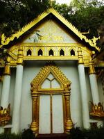 Old traditional ethnic building with gold archway and gold trim. There is a lush plant on the background. photo