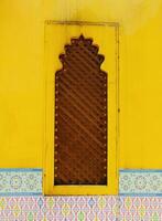 Classic traditional yellow window with a wooden frame and a lattice design. The door is open and the frame is brown. Vintage background. photo