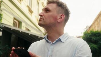 Caucasian man guy businessman smiling tourist traveler using smartphone gadget navigator app explore city guide mobile phone gps online geo map search address direction outdoor travel location outside video