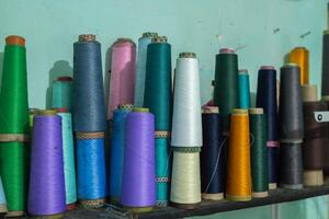 Spools of thread standing on a shelf photo