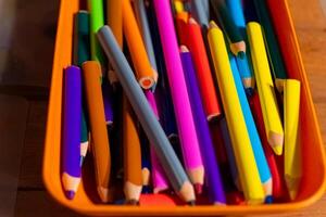 Vibrant colored pencils arranged in an orange box on a wooden surface, inviting creativity and artistic expression photo
