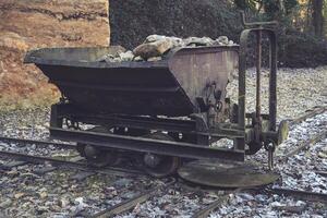 Old mining cart on abandoned tracks surrounded by nature in a remote area photo