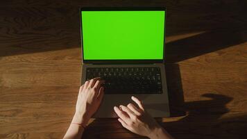 Top view of a woman hand swiping on a laptop computer touchpad with green screen chroma key video